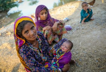 Uma mãe de quatro filhos sentada perto da água da enchente, depois de fugir da enchente, chegou em casa. Ela e a sua família refugiaram-se à beira da estrada no distrito de Jacobabad, província de Sindh, Paquistão. UNICEF/Zaidi