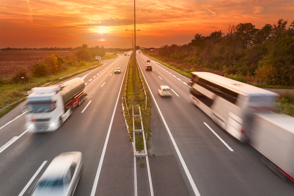 Foto panorâmica do tráfego de uma rodovia com ônibus e caminhões
