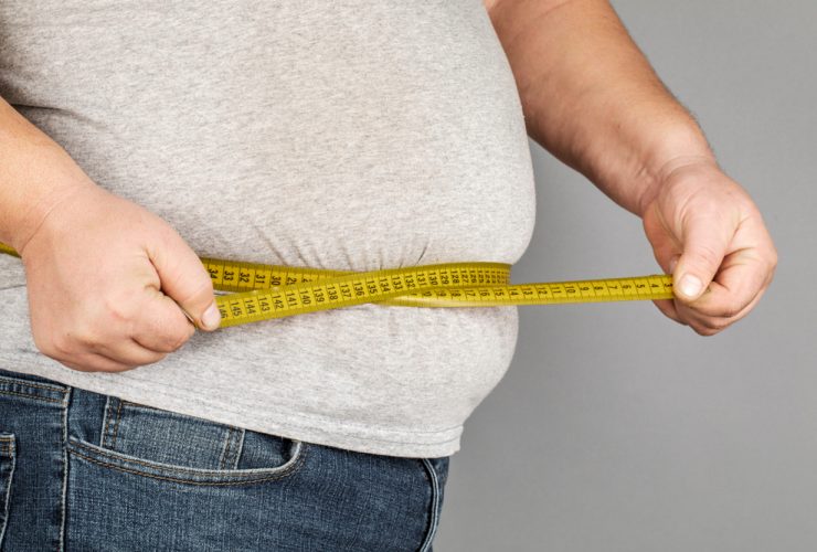Homem com obesidade, medindo a barriga com uma fita métrica