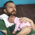 Pai cuidando da filha recém-nascida