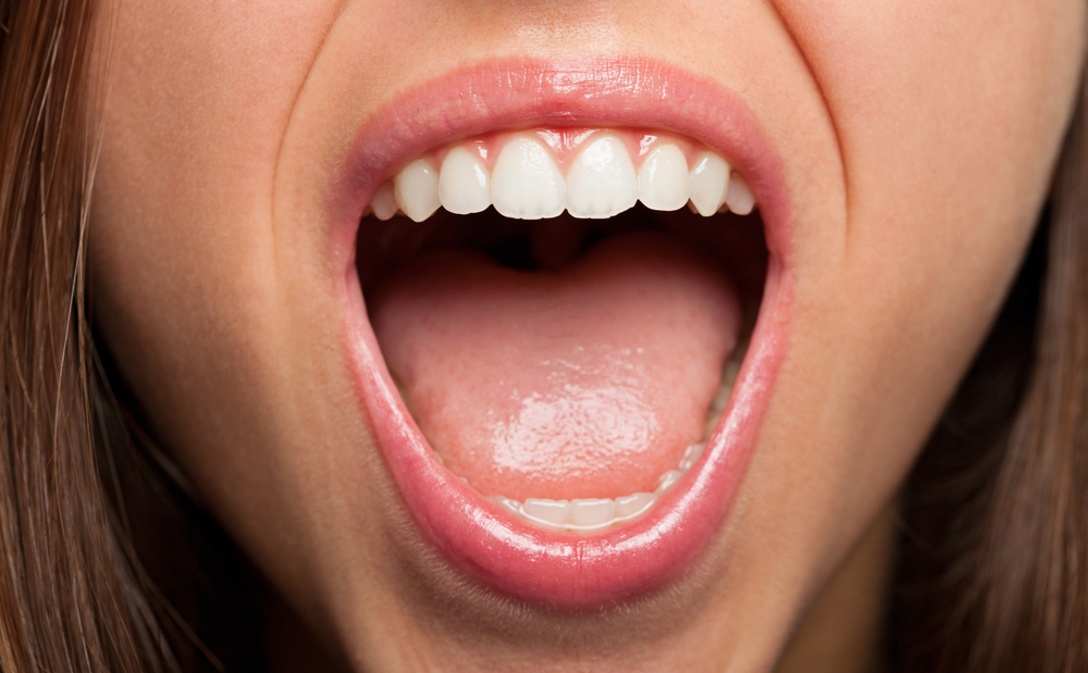 Boca de uma pessoa aberta mostrando os dentes e a língua