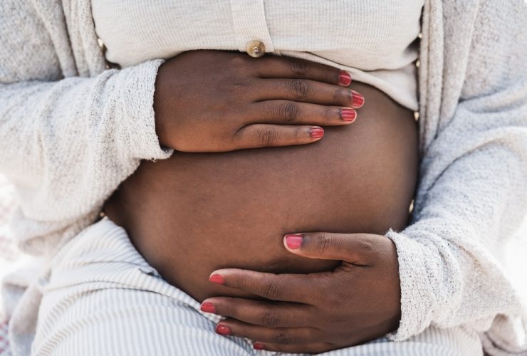 Mulher negra grávida segurando a barriga