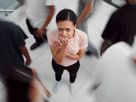 Foto de uma jovem com doença mental enquanto estava cercada por pessoas lá dentro Por YuriArcursPeopleimages