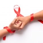 Duas pessoas de mãos dadas com o símbolo de combate ao HIV/AIDS