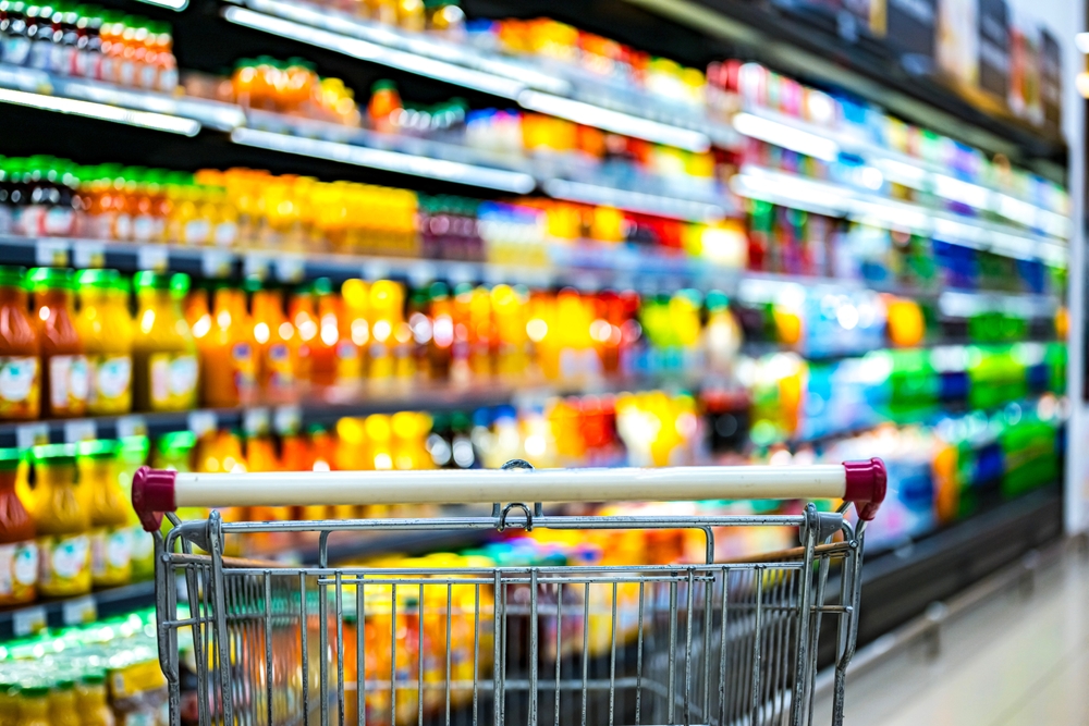 Um carrinho de compras e uma prateleira de alimentos de um supermercado