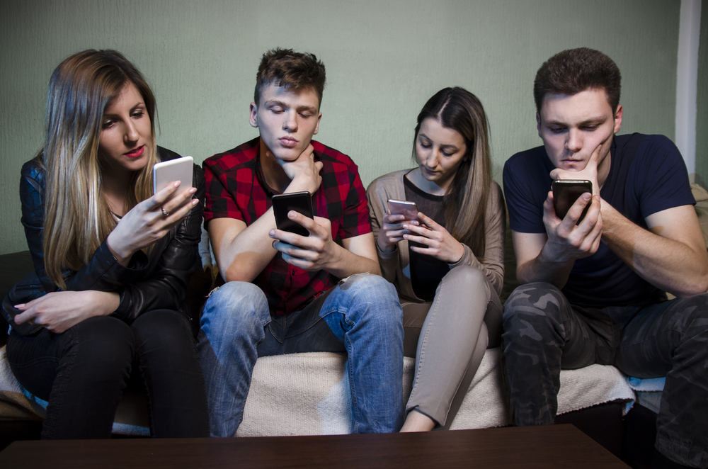 Um grupo de adolescentes olhando para os celulares