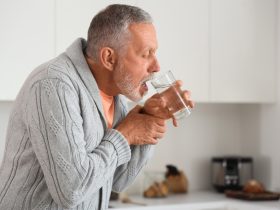 Homem com dificuldade de beber devido à doença de Parkinson