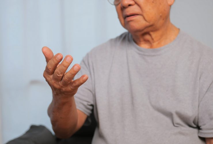 A mão de um homem idoso está tremendo por causa da doença de Parkinson. Por rthanuthattaphong