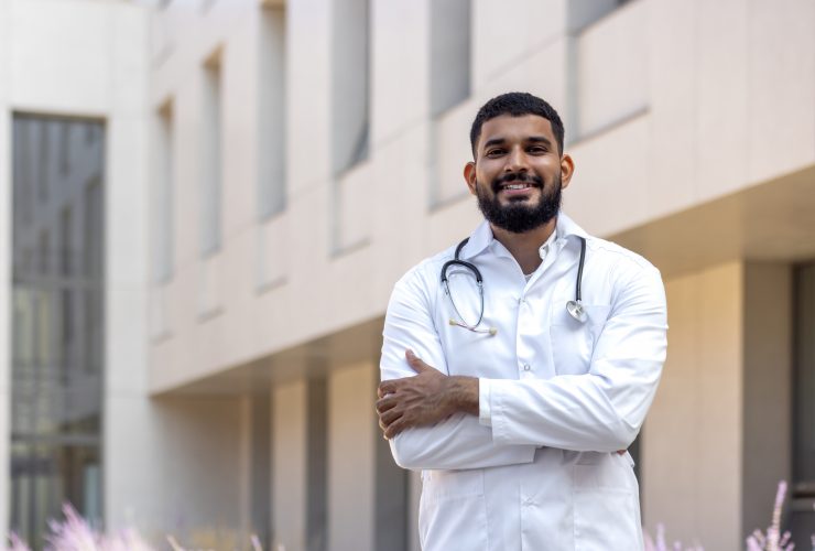 Retrato de um jovem estudante de medicina, um estagiário em pé do lado de fora do prédio médico e olhando Por voronaman111