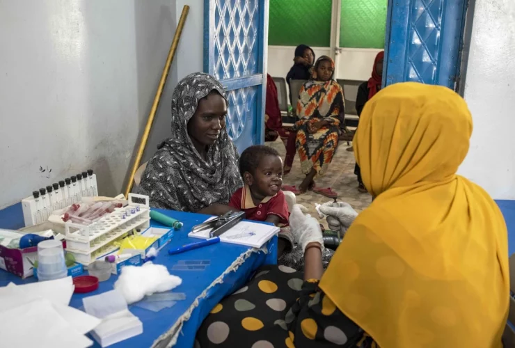 Uma mãe leva seu filho para um exame de sangue em uma unidade de saúde para mulheres e crianças no campo de IDP Abu Shouk, em Darfur do Norte. Em 2003, um conflito eclodiu em Darfur e forçou milhões de pessoas a fugir de suas casas | Foto de Lindsay Mackenzie para OMS