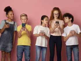 Tecnologias modernas na educação. Crianças multiétnicas usando celulares juntos sobre fundo rosa Por Prostock-studio