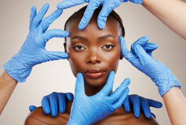 Retrato, mãos e cirurgia plástica para mudança com uma paciente negra em estúdio com um dorso cinza Por YuriArcursPeopleimages