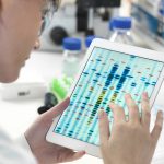 Cientista feminina examinando resultados de sequências de DNA em tablet digital em laboratório Por Image-Source