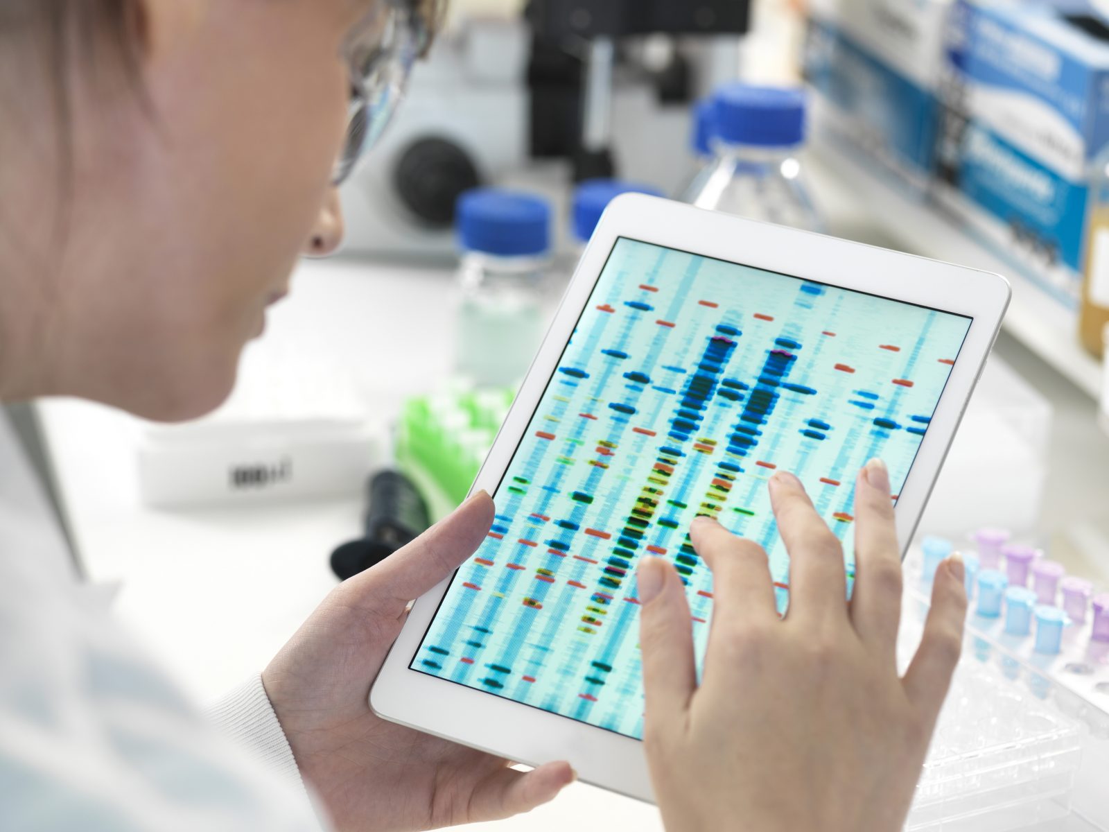 Cientista feminina examinando resultados de sequências de DNA em tablet digital em laboratório Por Image-Source