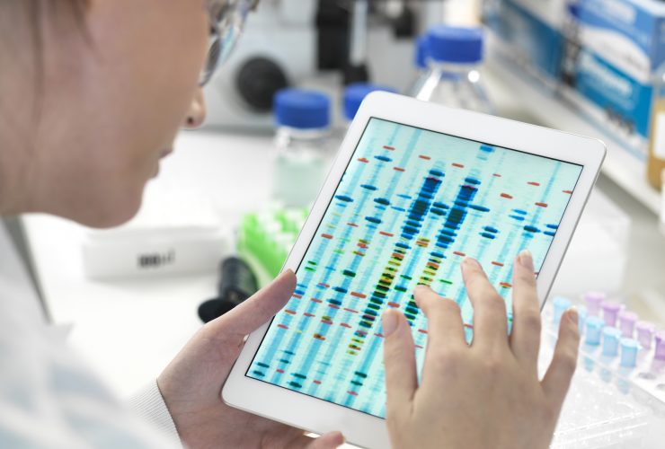 Cientista feminina examinando resultados de sequências de DNA em tablet digital em laboratório Por Image-Source