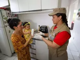 Imagem de uma mãe segurando sua bebê. As duas realizam a entrega do leite materno à Fundação Santa Casa, que tem parceria com o Corpo de Bombeiros Militar.
