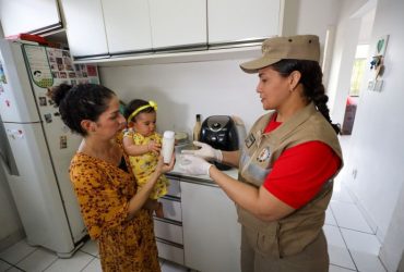 Imagem de uma mãe segurando sua bebê. As duas realizam a entrega do leite materno à Fundação Santa Casa, que tem parceria com o Corpo de Bombeiros Militar.