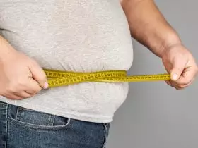 Homem com obesidade, medindo a barriga com uma fita métrica