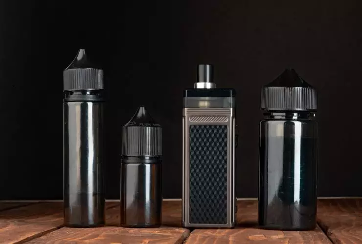 Vape e garrafas de líquido vape contra fundo preto Por FabrikaPhoto