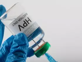 Composição da seringa de enchimento das mãos enluvadas do médico do frasco da vacina contra o HPV, em branco com espaço de cópia Por Wavebreakmedia