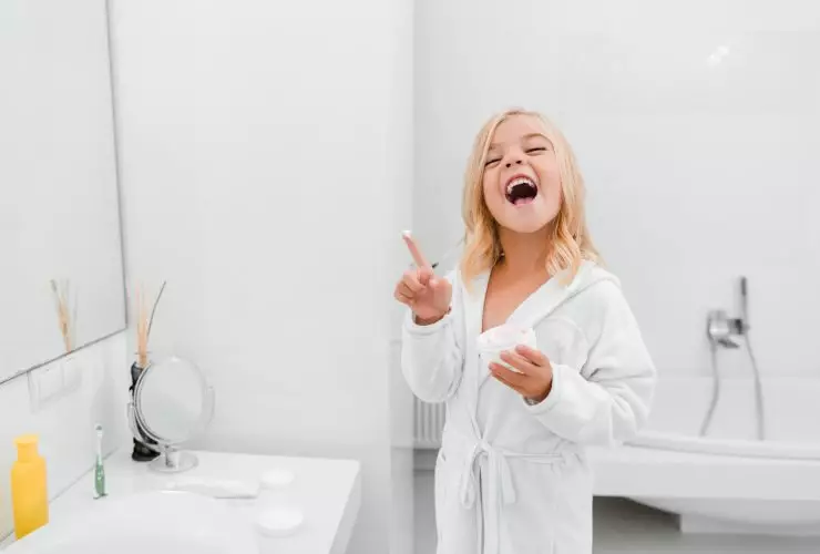 criança feliz com creme cosmético no dedo rindo no banheiro Por LightFieldStudios