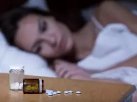 Mulher toma medicamentos para dormir
