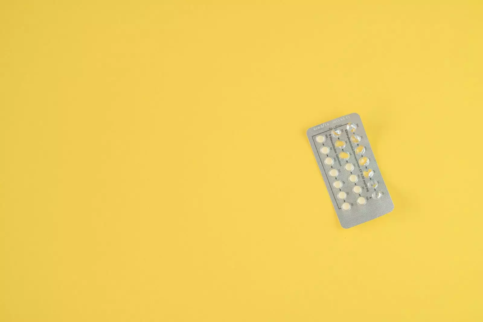 Pílulas anticoncepcionais orais femininas no fundo amarelo. Por SmitBruins