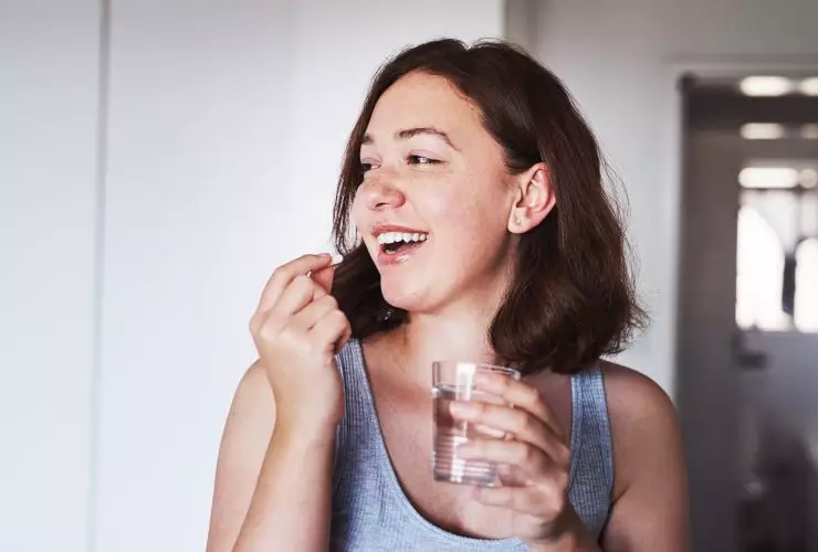 Faça o que for preciso para manter uma boa saúde. foto recortada de uma jovem tomando medicamentos em casa. Por YuriArcursPeopleimages