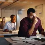 Foto de um jovem empresário parecendo estressado enquanto trabalhava até tarde em um escritório Por YuriArcursPeopleimages